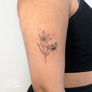 Elegant fine line tattoo featuring a bee and flower design, skillfully crafted by tattoo artist Chloe Mickham.