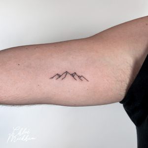 Get mesmerized by the dainty beauty of this fine line mountain tattoo, skillfully done by Chloe Mickham.