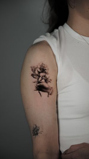 Exquisite black and gray micro realism tattoo of a hand holding a beautiful bundle of roses, created by Viola.