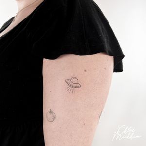 Embrace the mystery of the cosmos with this dainty fine line UFO tattoo. Intricately detailed by tattoo artist Chloe Mickham.