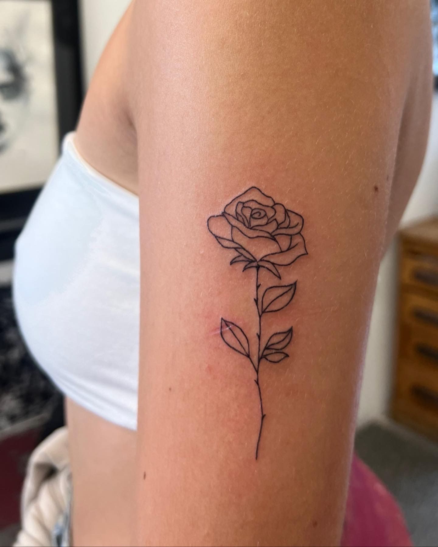 Fine line rose tattoo on the inner forearm
