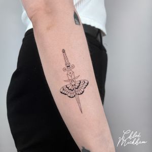 Elegant fine line tattoo featuring a detailed moth and dagger design, created by the talented artist Chloe Mickham.