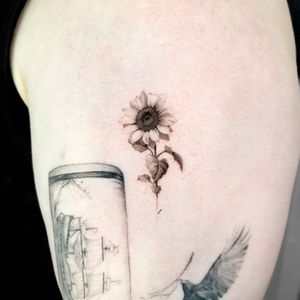 Experience the beauty of micro realism with this stunning black and gray sunflower tattoo by the talented artist Viola.