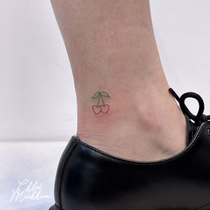 Elegant and delicate fine line tattoo of a heart entwined with cherries, by Chloe Mickham.