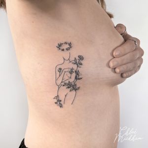 Elegant fine line tattoo featuring a beautiful woman surrounded by intricate nature and flowers, expertly done by Chloe Mickham.