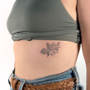 Exquisite fine line tattoo of a delicate flower and hop, expertly crafted by Chloe Mickham.