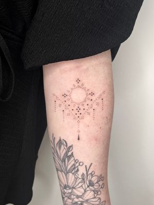 Get a radiant hand-poke sun with intricate ornamental patterns on your forearm by Indigo Forever Tattoos.