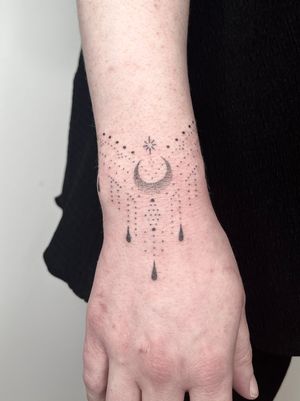Indigo Forever Tattoos created a beautiful hand-poke ornamental design featuring a moon motif and intricate patterns on the forearm.