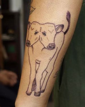 Unique forearm tattoo featuring a fine line design of a two-headed calf, created by Nikki Bostin.