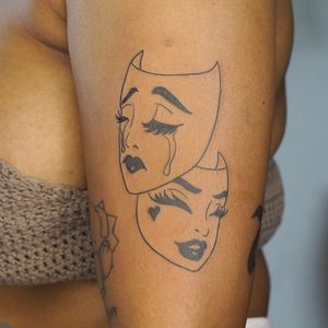 Get a stunning upper arm tattoo of a happy sad mask in fine line style by artist Nikki Bostin. Make a bold statement with this unique design.