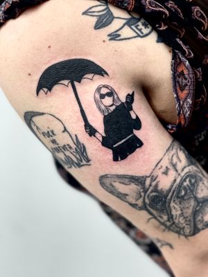 Elevate your style with this striking upper arm tattoo by Miss Vampira, featuring a captivating blend of umbrella and woman motifs in intricate blackwork design.