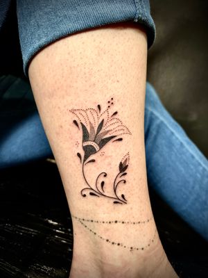 Elegant hand-poked flower design on the forearm by Indigo Forever Tattoos, creating a unique and personalized piece of art.