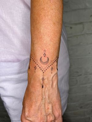 Ornamental hand-poked design by Indigo Forever Tattoos, featuring intricate moon and pattern detailing.