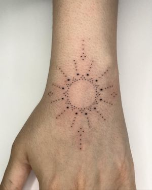 Elegant hand-poked forearm tattoo featuring a sun and ornamental pattern done by the talented artist Indigo Forever Tattoos.