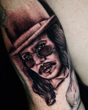 Capture Johnny Depp's essence with a stunning black and gray portrait on your upper arm. Expertly done by tattoo artist Miss Vampira.