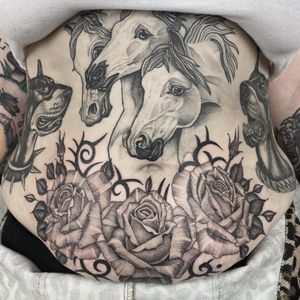 Elegant black and gray tattoo by Letitia Mortimer featuring a majestic horse and delicate flower design on the stomach.