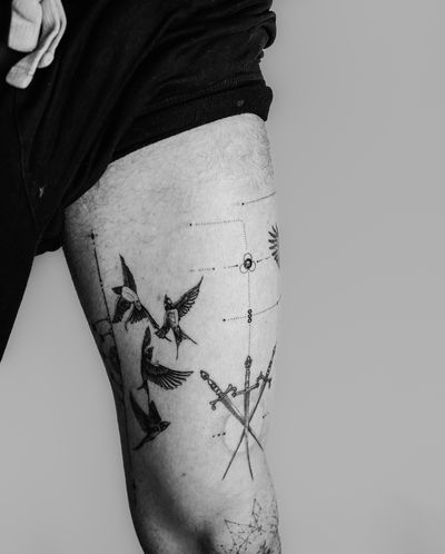 Intricate black and gray design by Gabriele Edu featuring a fine line micro-realism bird and sword motif on the upper leg.