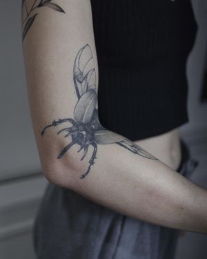 Get a realistic black and gray scarab with wings inked on your arm by the talented artist El Bernardes.