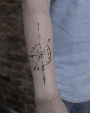 Fine line compass tattoo by El Bernardes featuring a circle design on the forearm.