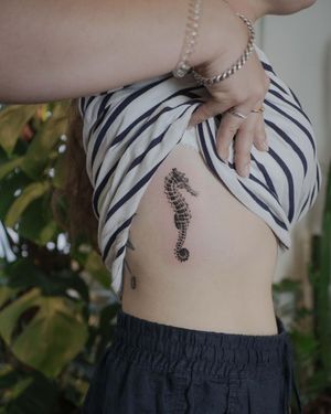 Get mesmerized by El Bernardes' micro realistic sea themed tattoo featuring a delicate seahorse on the ribs.
