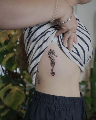 Get mesmerized by El Bernardes' micro realistic sea themed tattoo featuring a delicate seahorse on the ribs.