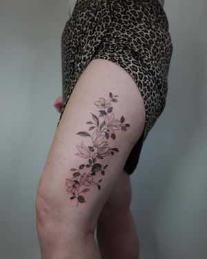 Elegant floral design on upper leg, expertly crafted with fine lines by tattoo artist El Bernardes.