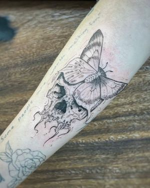 Unique blackwork design combining a delicate butterfly with a edgy skull motif by tattoo artist Hana Kaki.