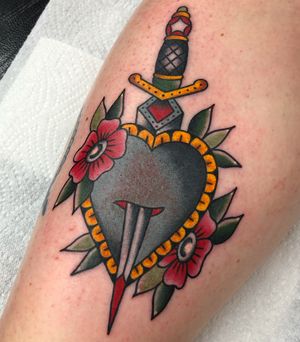Get inked by Carlos Zucato with a classic heart and dagger design on your forearm. Perfect for lovers of traditional tattoos.