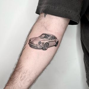 Capture the sleek lines of a Porsche 911 with this intricate upper arm tattoo by artist Martin Rosenberg.
