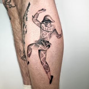Get a unique black and gray tattoo of a harlequin jester on your lower leg by the talented artist Martin Rosenberg.