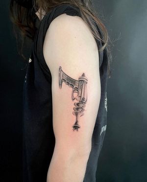 Fine line black and gray tattoo of a futuristic laser gun on the upper arm by Martin Rosenberg.