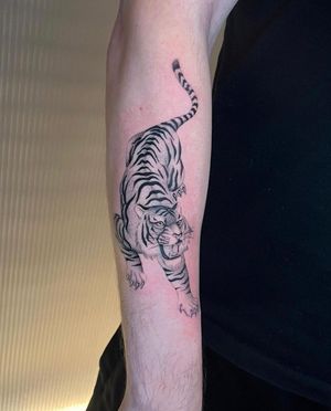 Get a fierce yet elegant touch with this black and gray tiger tattoo on your lower arm. Designed by Martin Rosenberg.