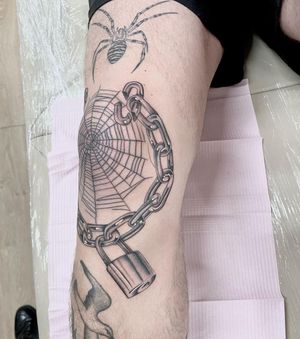 Discover the intricate design of a chain and padlock in a stylish black and gray fine line technique, created by tattoo artist Martin Rosenberg.
