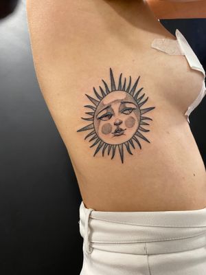 Elegant sun design on the ribs by Victor Martin using intricate dotwork and fine line techniques.