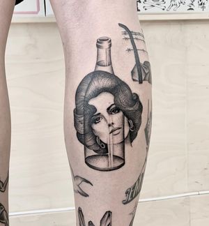 Capture the beauty and mystery of a lady holding a bottle with this stunning black and gray tattoo by Martin Rosenberg. Perfect for the lower leg.