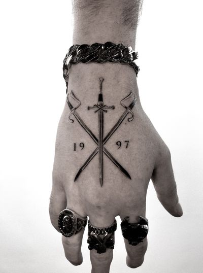 Hand tattoo by Jay Soze featuring small lettering and numbers for a unique and intricate design.