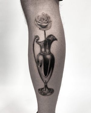 Elegant lower leg tattoo by Jay Soze featuring a stunning flower in a vase, in classic black and gray style.
