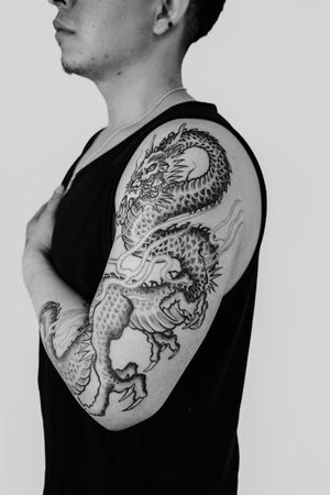 Experience the power and beauty of a black and gray Japanese dragon tattoo on your upper arm by Gabriele Edu.