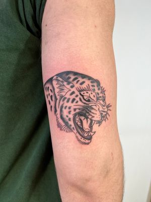 Get a fierce jaguar inked on your upper arm by Kayleigh Cole. A unique blend of traditional and black and gray styles.