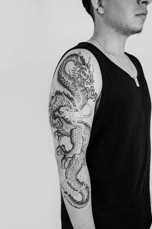 This stunning black and gray Japanese dragon tattoo on the upper arm was beautifully executed by the talented artist Gabriele Edu.
