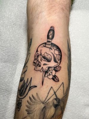 Traditional black and gray calf tattoo featuring a skull and dagger, expertly done by Kayleigh Cole.