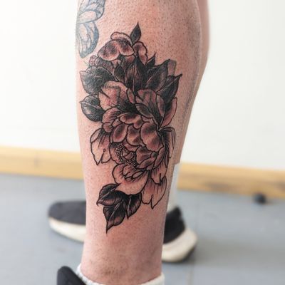Beautiful floral design by George Antony on lower leg, featuring a detailed peony flower motif.