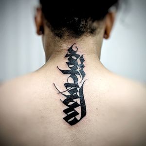Beautiful blackwork tattoo on upper back combining a meaningful quote with intricate patterns by Chun Lee.
