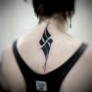 Elegantly detailed upper back tattoo featuring a unique blackwork pattern and sign design by the talented artist Chun Lee.