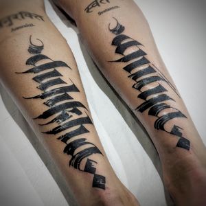 Elegant blackwork style tattoo featuring a unique pattern and lettering of a name, expertly done by tattoo artist Chun Lee.