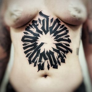 Discover the intricate blackwork pattern and inspiring quote on stomach, crafted by tattoo artist Chun Lee.