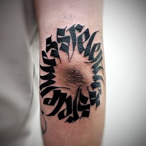 Get a unique blackwork design on your elbow with a meaningful quote by talented artist Chun Lee.