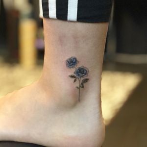 Elegant fine line flower design by tattoo artist Hansol Jung for a subtle and feminine ankle tattoo.