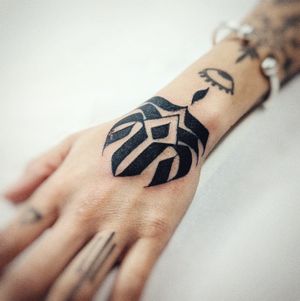 Experience the bold beauty of blackwork tribal art with this intricate hand tattoo by Chun Lee.