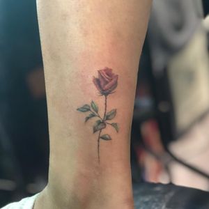 Elegant flower design by Hansol Jung, delicately inked on the ankle in a fine line style.